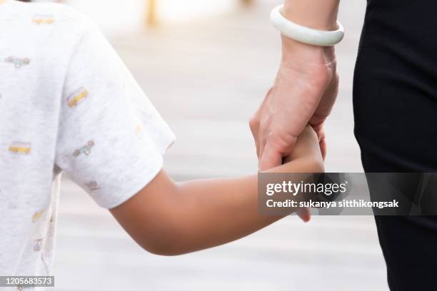 cropped shot of rear view a little girl holding  her mother"u2019s hand in the park. - girls hands behind back stock pictures, royalty-free photos & images