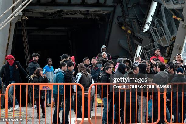 Migrants and refugees gather near a Greek military carrier docked at the port of Mytilene on the Greek Island of Lesbos on March 7 which is being...