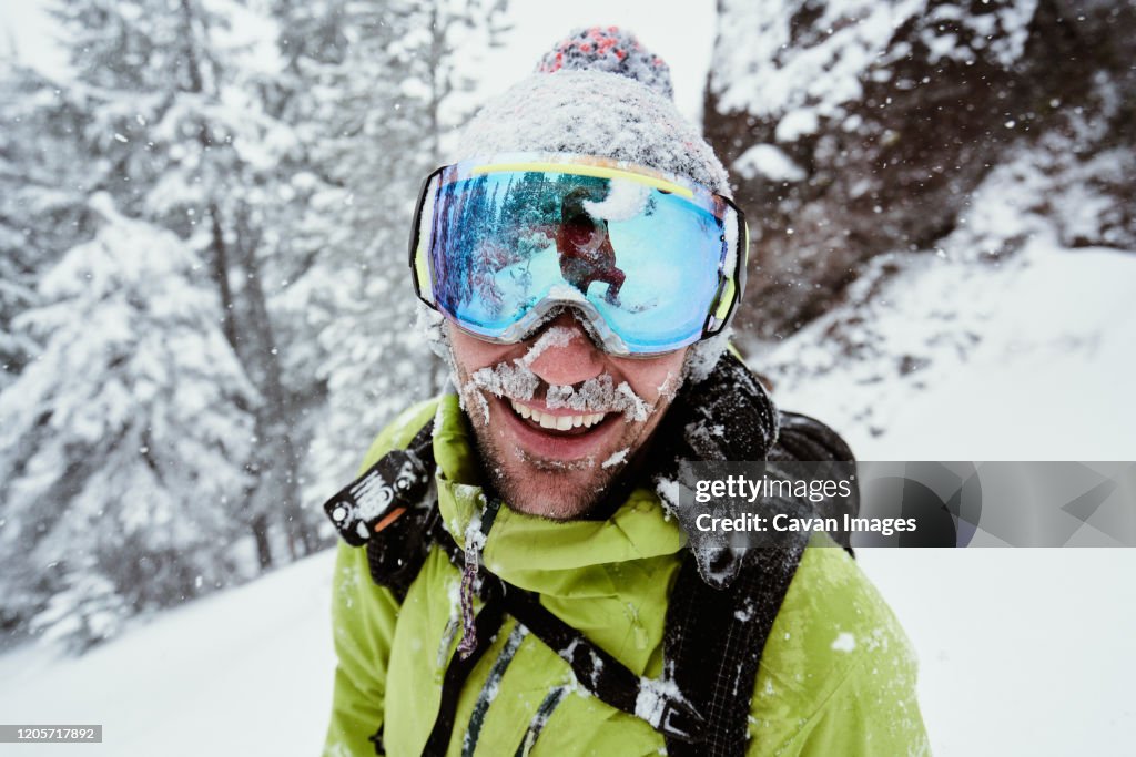Male Snowboarder Covered in Snow Smiling in Winter