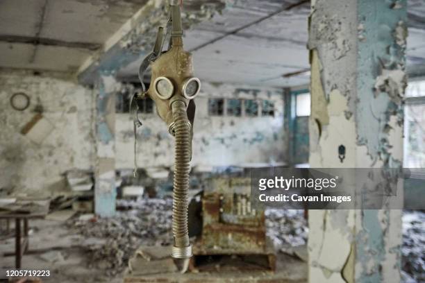 gas masks on the floor with an old television in an abandoned middle school in pripyat - chernobyl stock-fotos und bilder