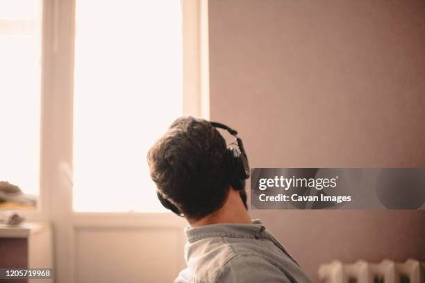 man looking through window while listening music working at home - wasting time stock pictures, royalty-free photos & images