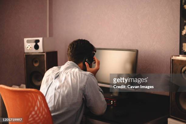 concentrated man listening music on headphones sitting by computer - mann vor pc stock-fotos und bilder