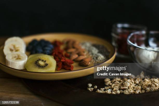 healthy and delicious plate of fruit, nuts and seeds with yogurt and gogi berries - gogi stock pictures, royalty-free photos & images