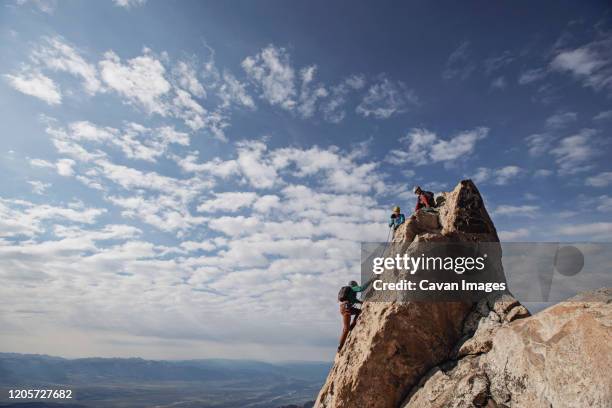 three rock climbers each the summit of a mountain in tetons, wyoming - teton range stock pictures, royalty-free photos & images