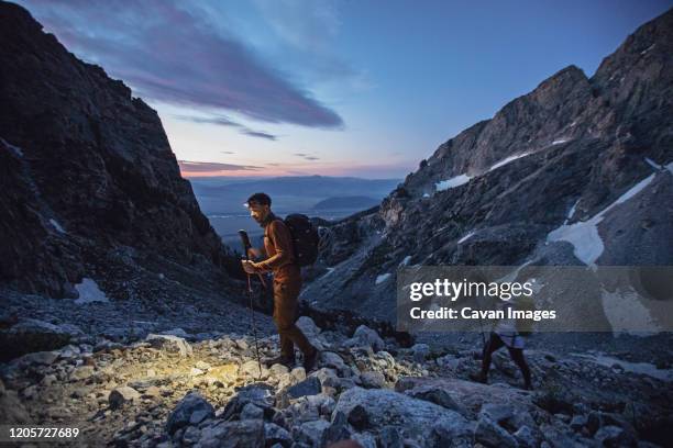 hikers walk with headlamps at sunrise in grand teton national park - grand teton stock-fotos und bilder