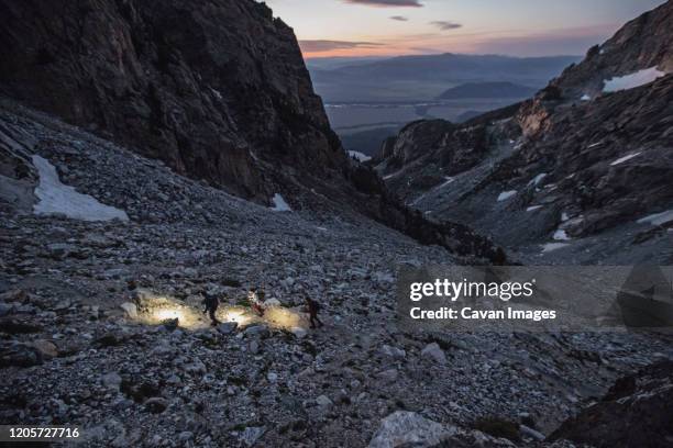 three hikers walk at dawn through a vast glacier rock field, wyoming - grand teton stock-fotos und bilder