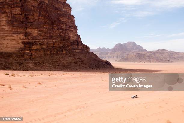 tourists explore the vastness of the wadi rum desert in jordan. - internationaal monument stockfoto's en -beelden