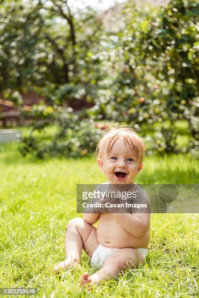 little boy siting on the grass and laughs - baby lachen natur stock-fotos und bilder