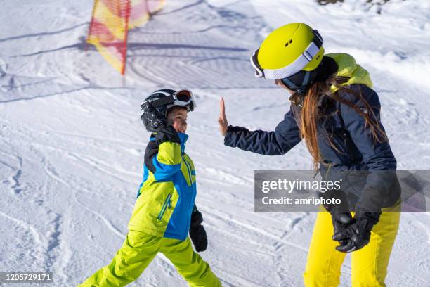 gelukkige skijongen die hoge vijf geeft aan zijn moeder op skipiste - happy skier stockfoto's en -beelden