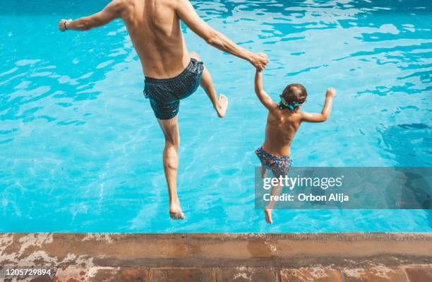 père et fils ayant l’amusement sur la piscine - piscine de complexe balnéaire photos et images de collection