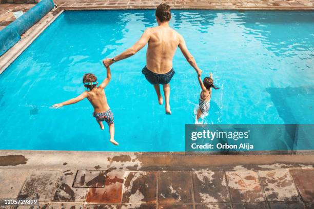 vater und sohn mit spaß am pool - jump in pool stock-fotos und bilder