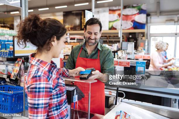 kassiererin im supermarkt - kundin zahlt mit kontaktloser kreditkarte - shop till stock-fotos und bilder