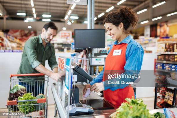 funcionário em caixa registradora em supermercado, atendendo o cliente - checkers - fotografias e filmes do acervo