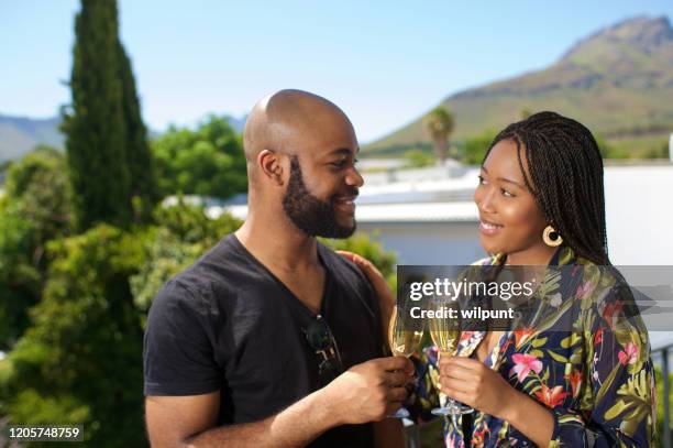 paar dat champagne samen heeft die zich hoog op een portiek het glimlachen bevindt - stellenbosch stockfoto's en -beelden