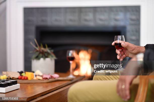 sitzen um den kamin mit einem getränk - sweet wine stock-fotos und bilder