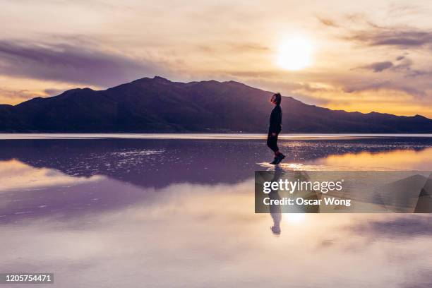 woman walking on salt flat against sky at salar de uyuni - uyuni stock pictures, royalty-free photos & images