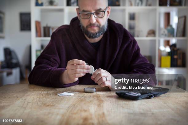 man using blood sugar measurement device to monitor diabetes - diabetes lifestyle stock-fotos und bilder