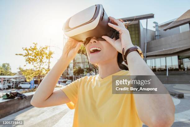 portrait of young asian woman wearing virtual reality goggles and enjoying the vr simulation experience. conceptual of vr reality technology. - vr goggles woman stock-fotos und bilder