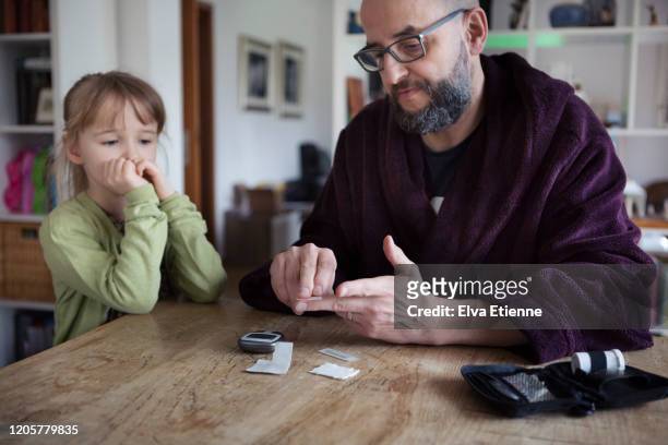 parent showing child how to use a blood sugar measurement device to monitor diabetes - childhood diabetes stock pictures, royalty-free photos & images