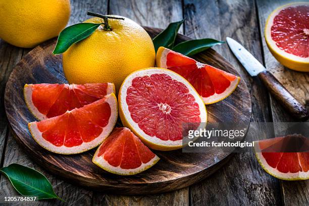 toda e fatiada de frutas de uva filmadas em mesa de madeira rústica - grapefruit red - fotografias e filmes do acervo