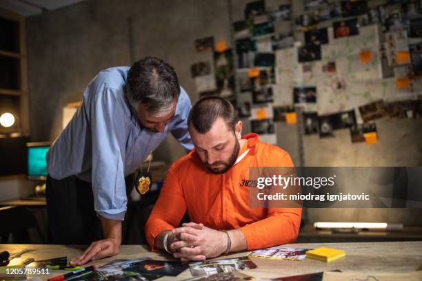 prisoner with handcuffs being interviewed in interrogation room - interrogation stock pictures, royalty-free photos & images