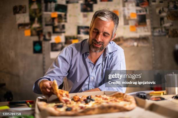 hungry fbi detective taking pizza slice after late night work in the office - fbi director stock pictures, royalty-free photos & images