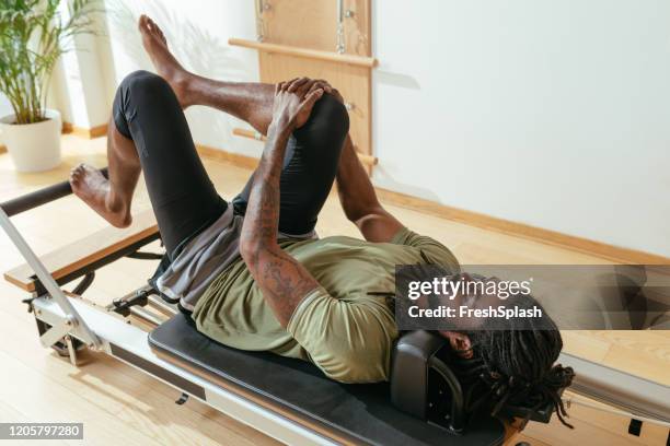 sportsman doing leg stretching exercise - reformer stock pictures, royalty-free photos & images