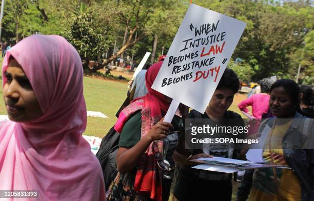 Woman holds a placard during the march. Women from various organizations, including tribal and dalit communities, gather in large numbers to take...