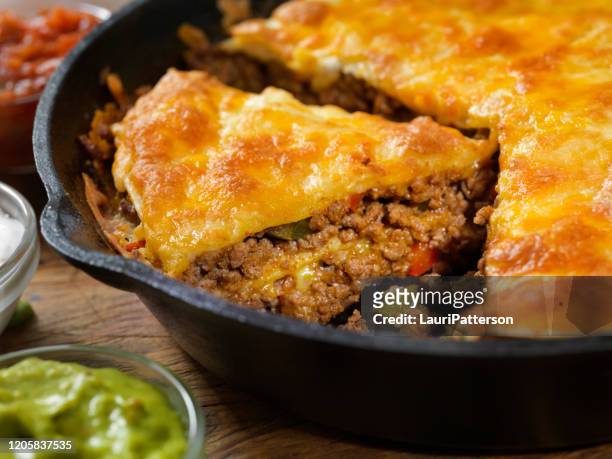 layered, beef taco pie baked in a cast iron skillet with sour cream, salsa and guacamole - savoury pie stock pictures, royalty-free photos & images