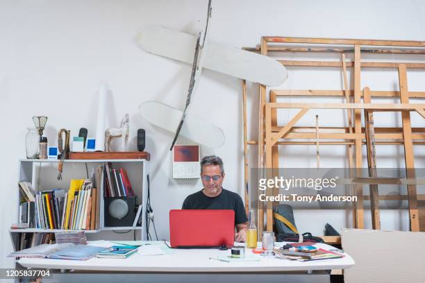 artist working on laptop in his studio - man sitting at a desk craft stockfoto's en -beelden