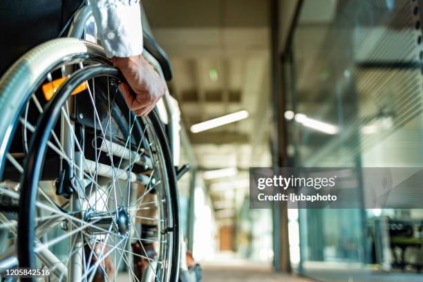 achtermening van onherkenbare persoon in een rolstoel in een gang - wheelchair stockfoto's en -beelden