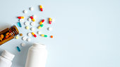 Medical bottles and medication pills spilling out on to pastel blue background. Top view with copy space. Healthcare, pharmacy, medicine concept
