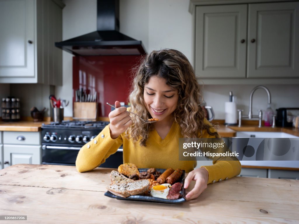 Mooie jonge vrouw thuis die van een heerlijk Engels ontbijt geniet
