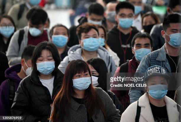 Passengers wearing face masks arrive at Changsha railway station in Changsha, the capital of Hunan province on March 8, 2020. - China on March 8...