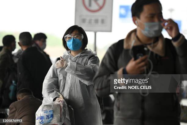 Passengers wearing protective facemaks arrive at the Changsha railway station in Changsha, the capital of Hunan province on March 8, 2020. / AFP...