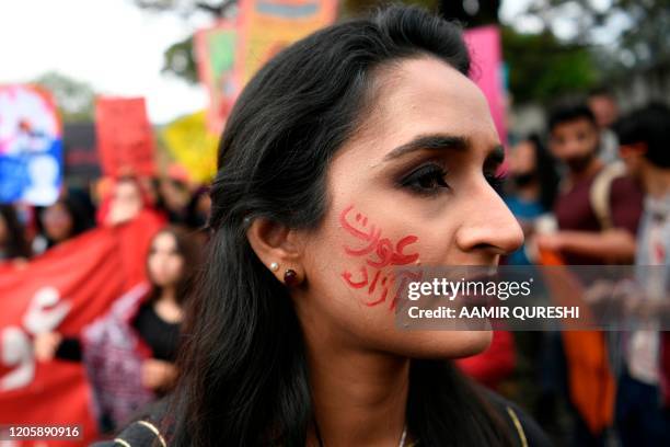 An activist of the Aurat March, with a slogan reading 'freed woman' painted in her face attend a rally to mark the International Women's Day in...