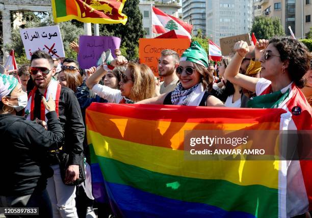 Supporters of the Lebanese LGBT community lift the rainbow flag during a march to mark International Women's Day in the capital Beirut, on March 8,...