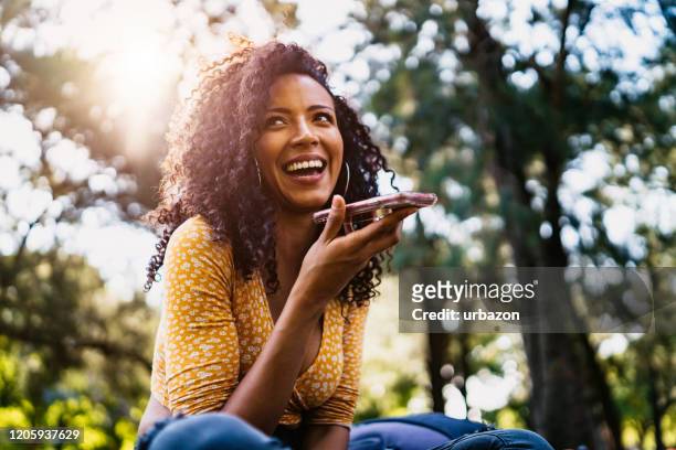 beautiful woman talking on phone in park - woman smartphone nature stock pictures, royalty-free photos & images