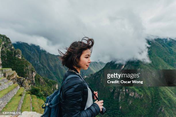 young woman looking at view from machu picchu in peru - reisbestemmingen stockfoto's en -beelden