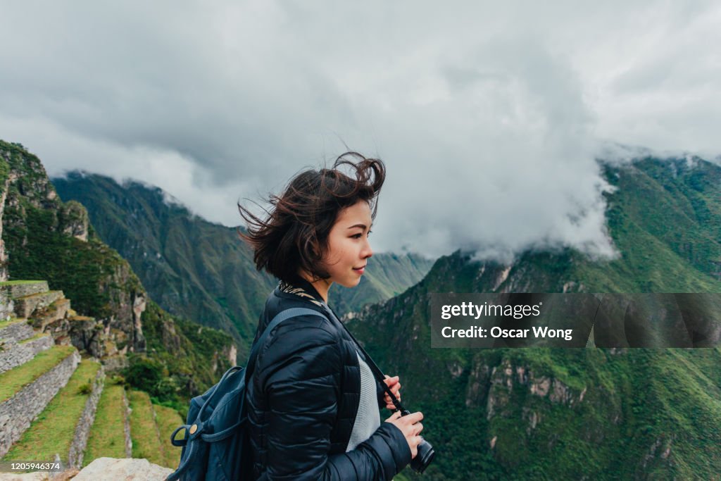 Young Woman Looking At View From Machu Picchu In Peru