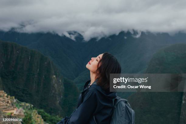young woman enjoying fresh air on the mountain of machu picchu in peru - paisajes de peru fotografías e imágenes de stock
