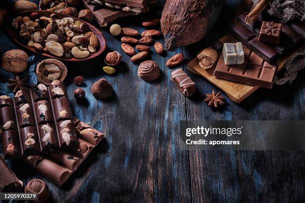 lågmäld bild av en mängd olika choklad och bombones med torkad frukt. gammaldags stil på ett blått rustikt bord med kopieringsutrymme - bombones chocolate bildbanksfoton och bilder