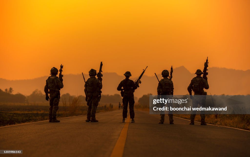 Silhouette soldiers on the sunset sky background