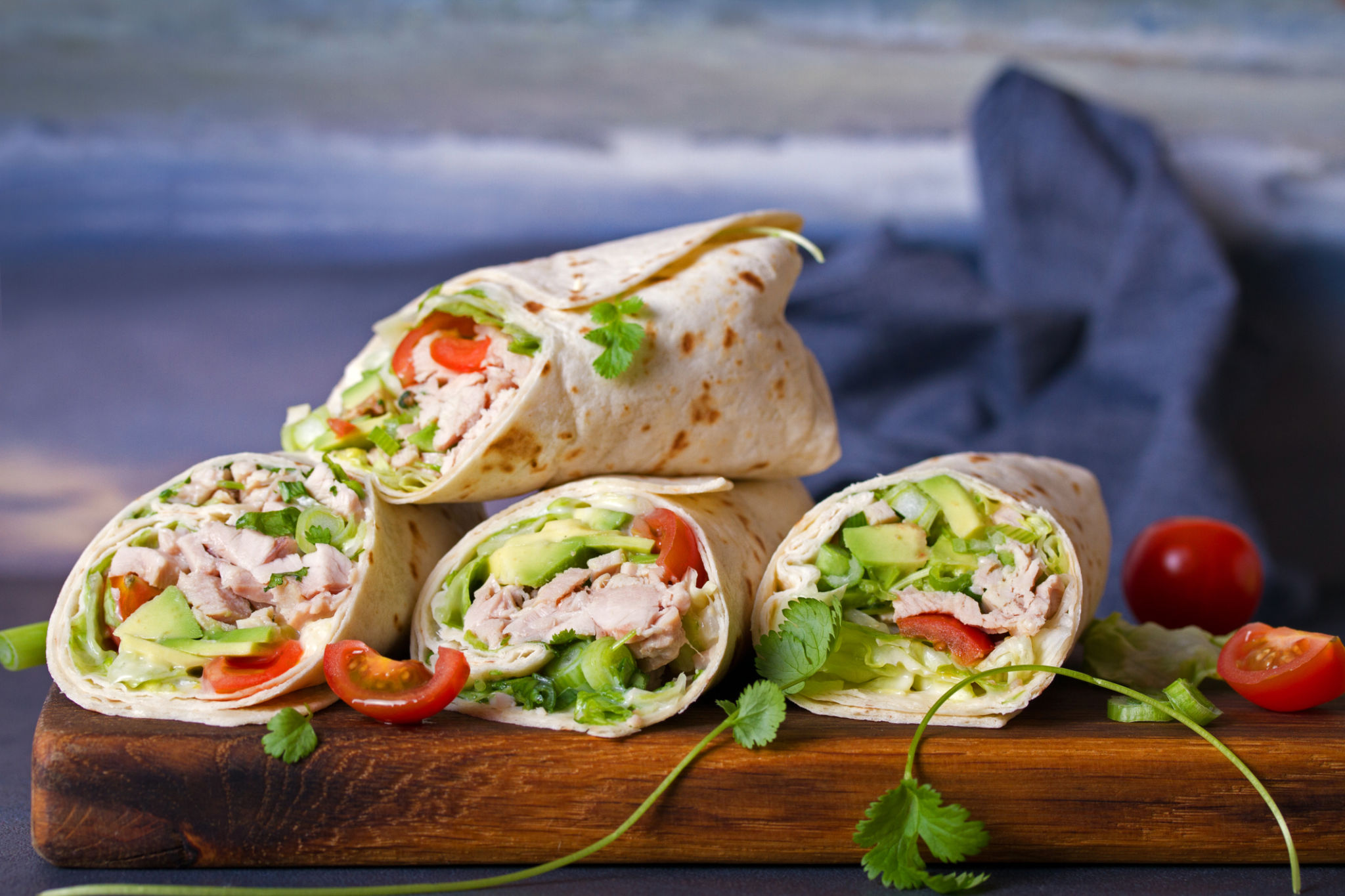 Turkey wraps with avocado, tomatoes and iceberg lettuce on chopping board Turkey wraps with avocado, tomatoes and iceberg lettuce on chopping board
