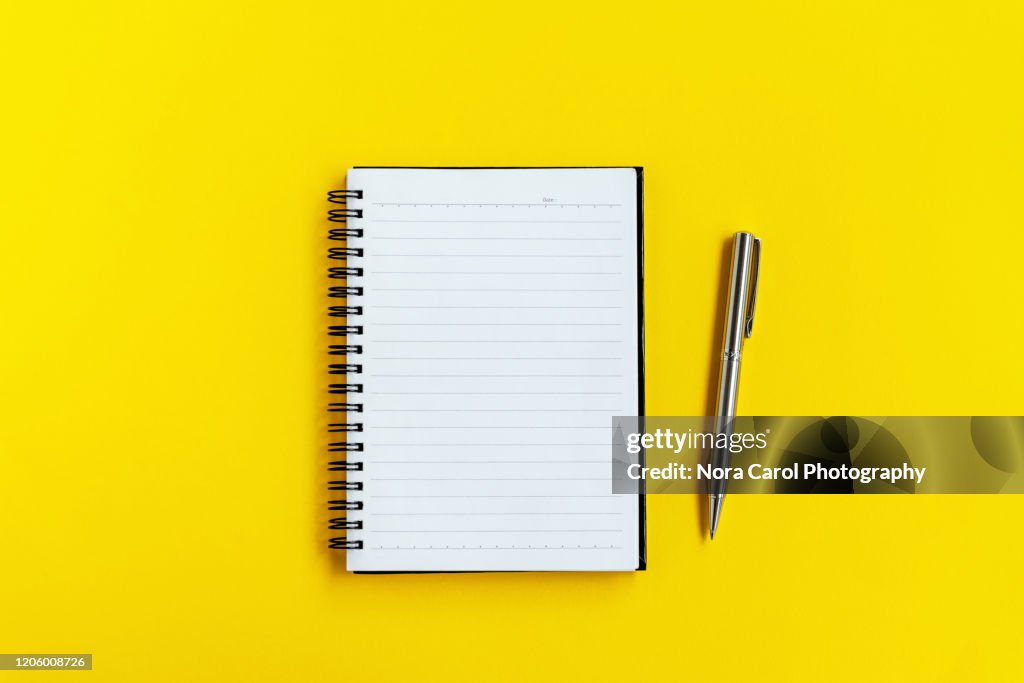 Note Pad and Pen on Yellow background