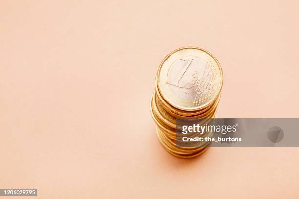 stack of one euro coins on brown background - one euro coin stock pictures, royalty-free photos & images