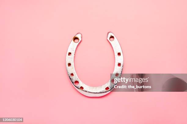 high angle view of a horseshoe on pink background - horseshoe stock-fotos und bilder