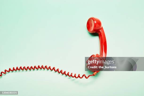 high angle view of a red old-fashioned telephone receiver with a coiled cable on turquoise background - old phone imagens e fotografias de stock