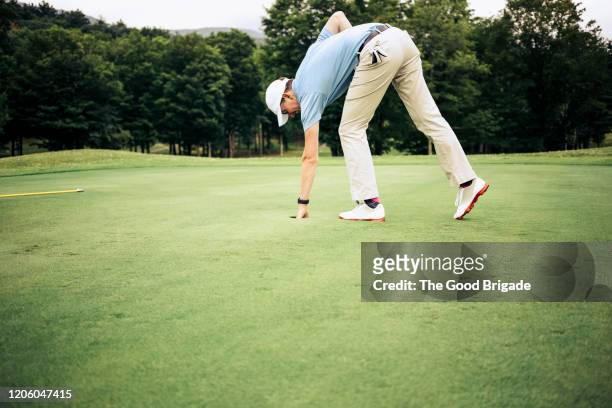 man removing golf ball from cup - putting green stock pictures, royalty-free photos & images