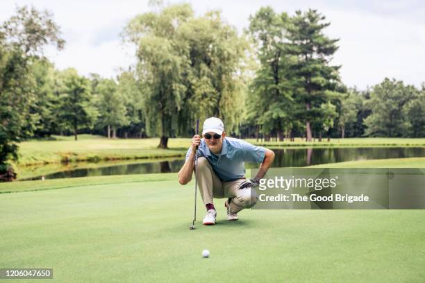 man lining up putt on golf course - golf putter stock pictures, royalty-free photos & images